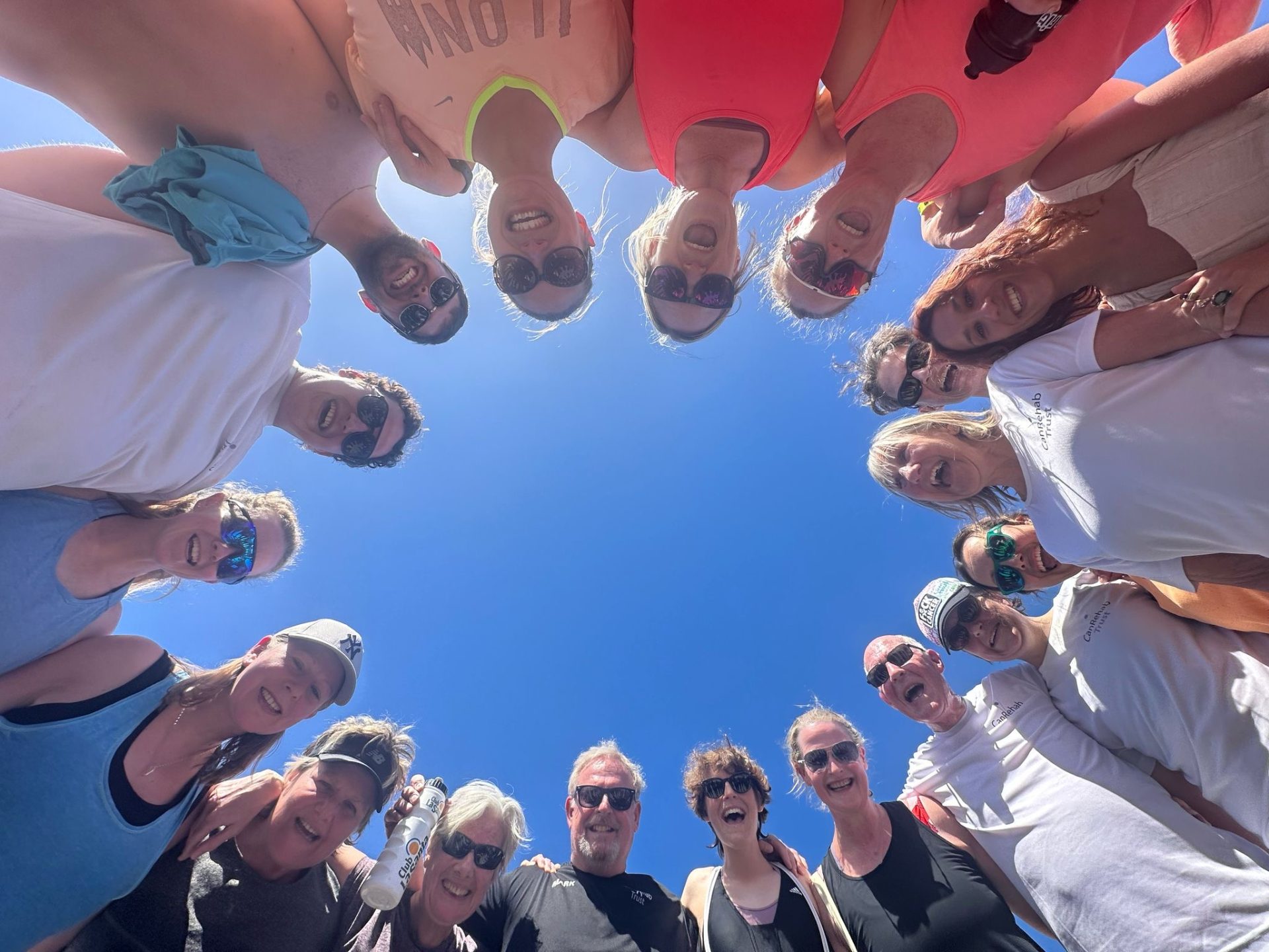 Participants huddled in a circle smiling down at the camera