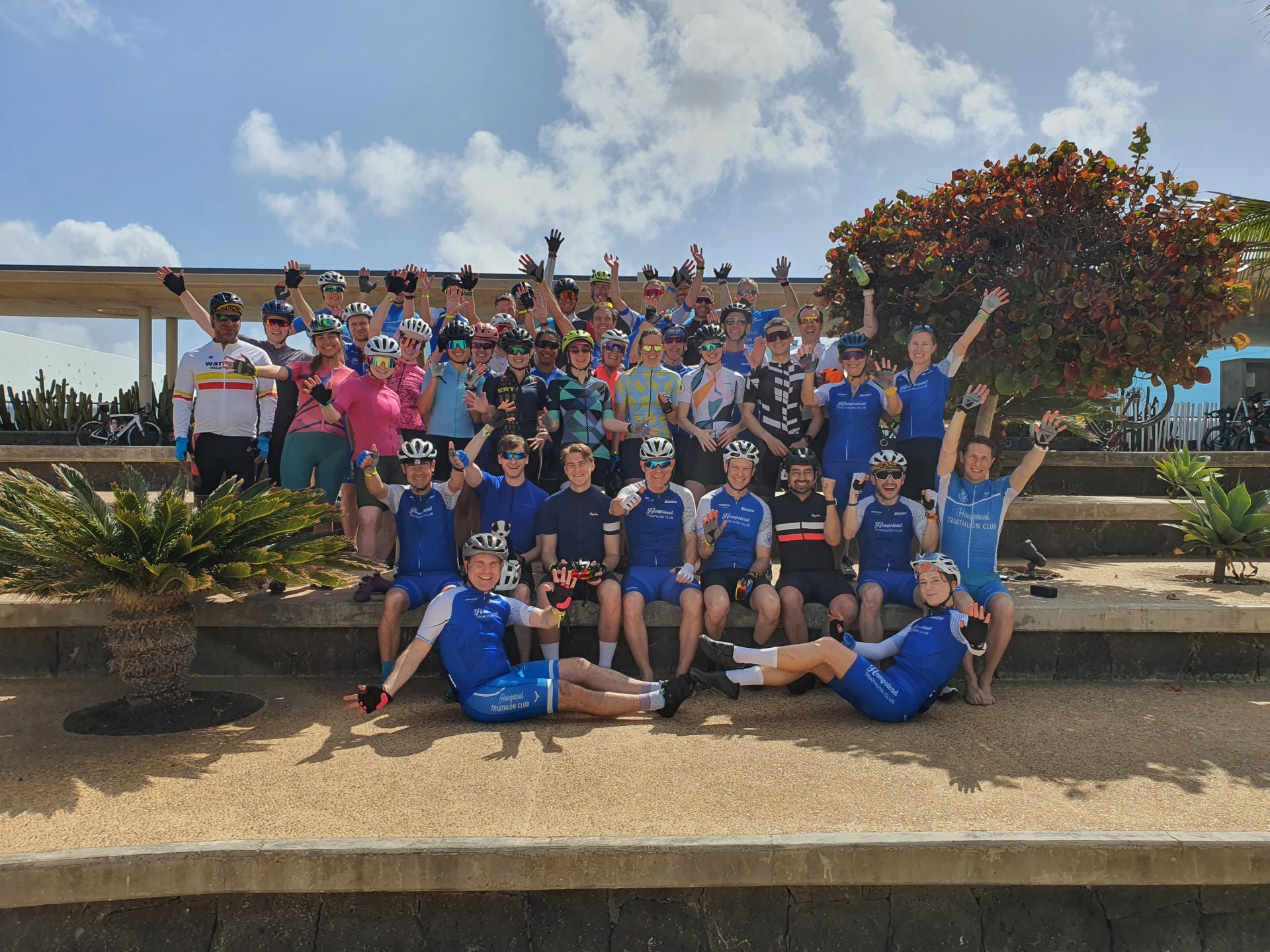 a group picture of participants on the triathlon camp together waving their hands and smiling at the camera