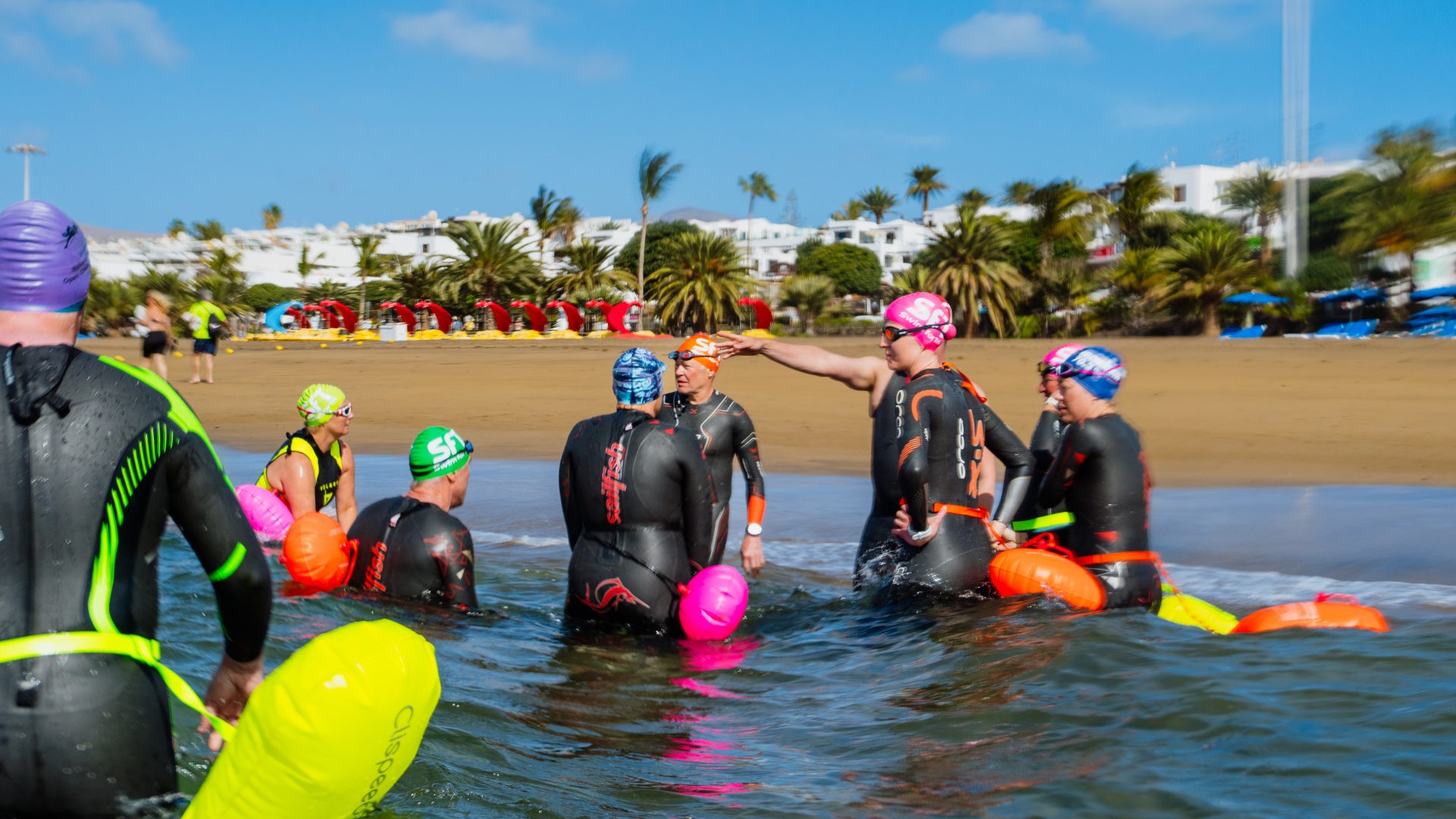 Participants of the open water swim camp at Club La Santa using various swimming equipment at the Lagoon